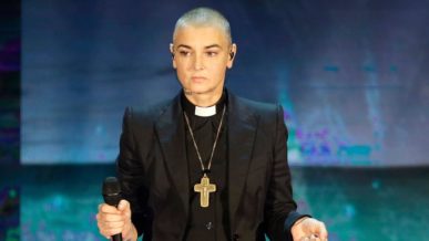 Sinead O'Connor wearing a Catholic priests uniform with shaved head hair