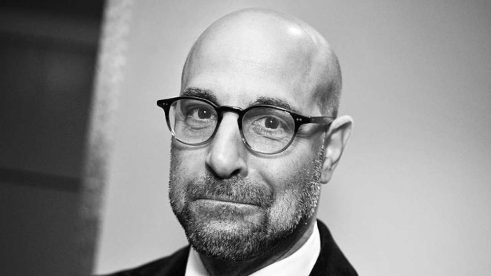 Stanley Tucci pictured bald head wearing glasses and sporting designer beard stubble
