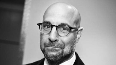 Stanley Tucci pictured bald head wearing glasses and sporting designer beard stubble