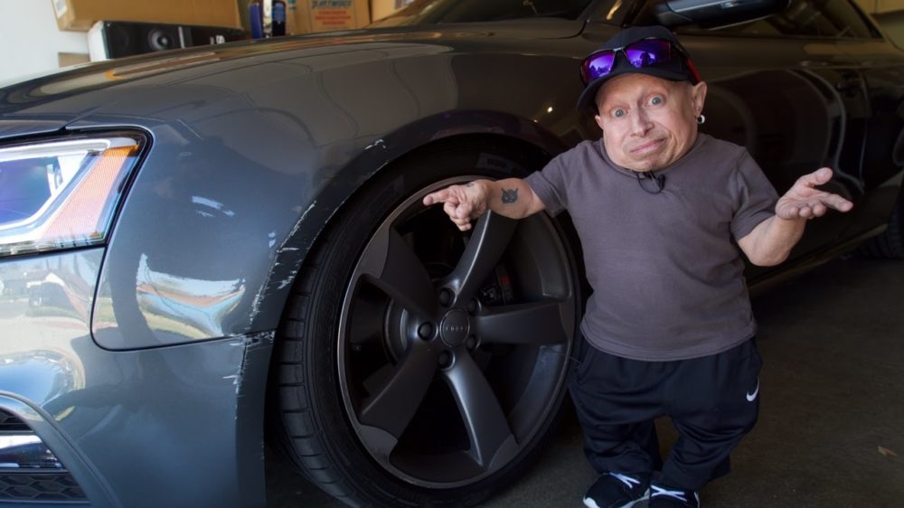 Verne Troyer pointing at damaged car